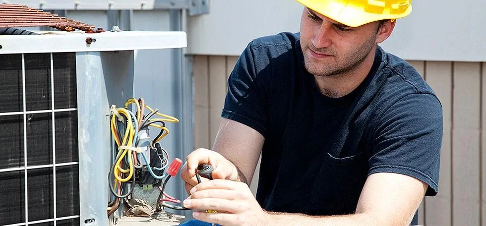 HVAC technician servicing outdoor AC condenser unit electrical components and wiring